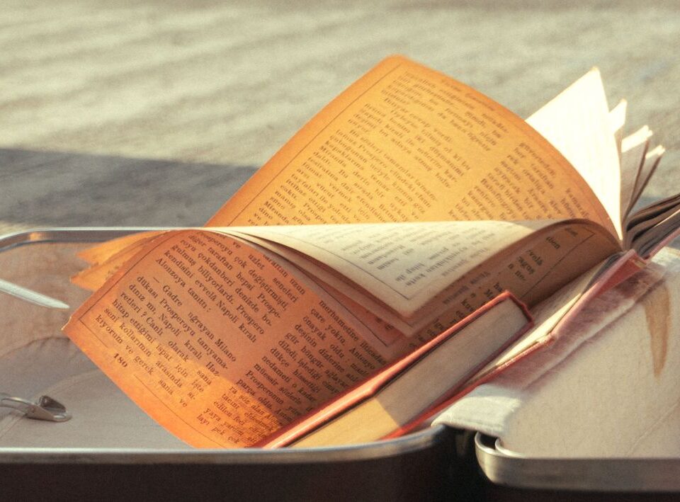 Отворена книга върху куфар на слънчева крайбрежна улица